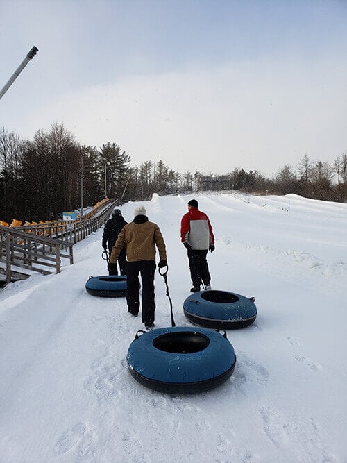 REM team members going up the snow-tubing hill